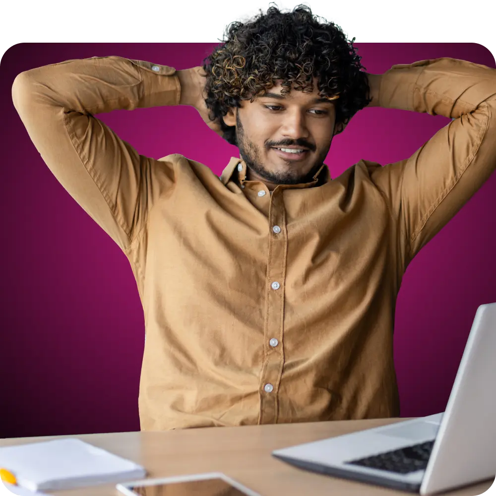 Man with his arms behind his head looking at his laptop